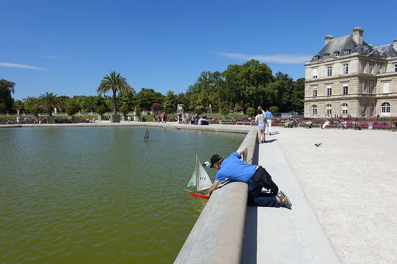 playing with a boat at jardin du luxembourg gardens by guilhem vellut